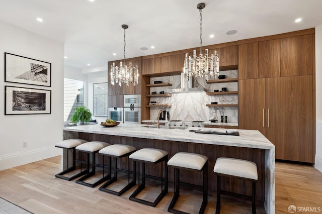 kitchen featuring a kitchen breakfast bar, an inviting chandelier, hanging light fixtures, and light hardwood / wood-style floors