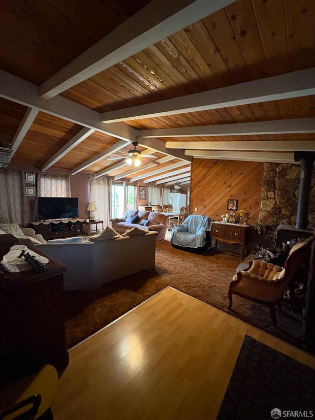 living room featuring ceiling fan, hardwood / wood-style floors, wooden walls, and vaulted ceiling with beams