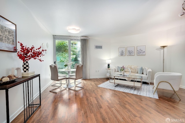 living room featuring visible vents, baseboards, and wood finished floors