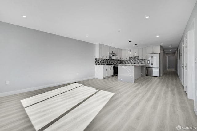 kitchen with under cabinet range hood, stainless steel refrigerator with ice dispenser, decorative backsplash, and open floor plan