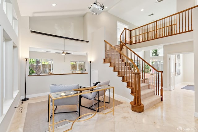 stairs with ceiling fan and high vaulted ceiling