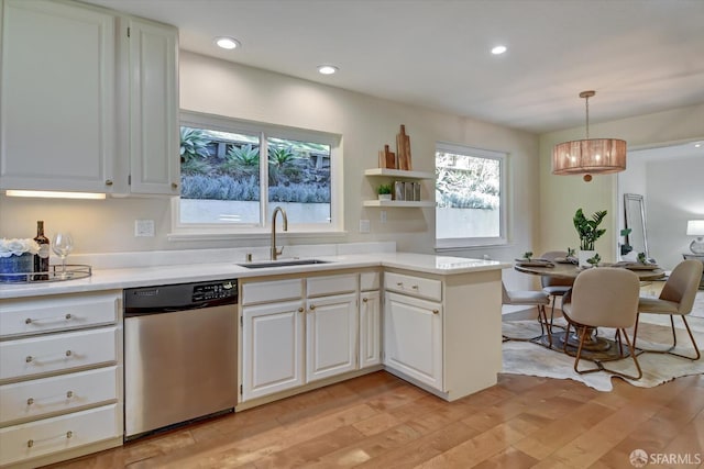 kitchen with decorative light fixtures, dishwasher, sink, white cabinets, and light hardwood / wood-style floors