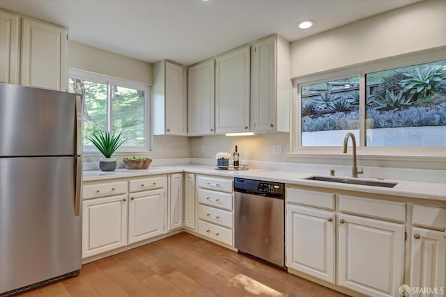 kitchen featuring stainless steel appliances, sink, white cabinets, and light hardwood / wood-style floors