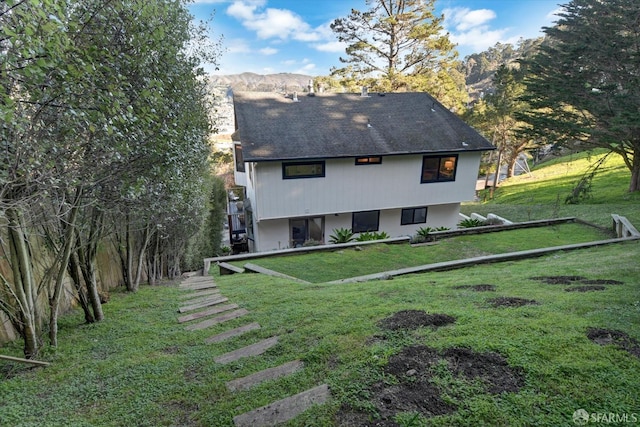 rear view of house with a mountain view and a yard