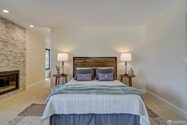 carpeted bedroom with a stone fireplace