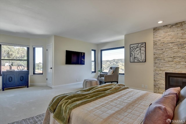 bedroom featuring light carpet and a fireplace