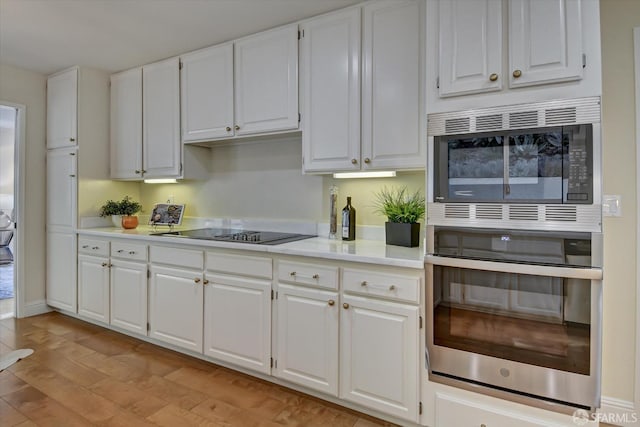 kitchen featuring white cabinetry, stainless steel microwave, black electric stovetop, and light wood-type flooring