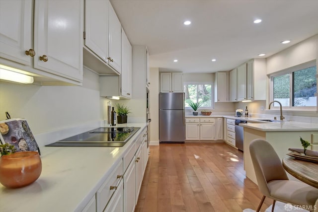 kitchen featuring a breakfast bar, sink, white cabinetry, light hardwood / wood-style flooring, and stainless steel appliances