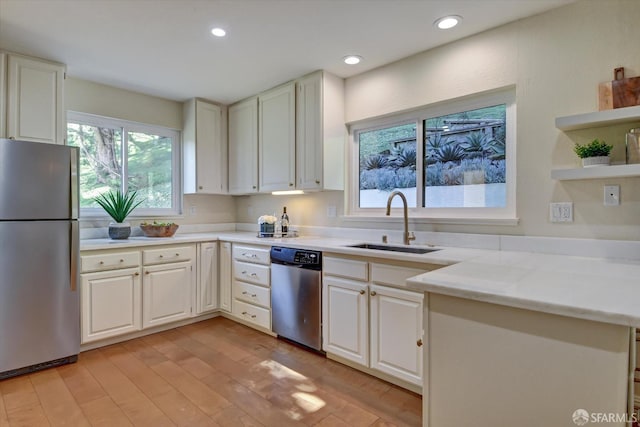 kitchen featuring sink, stainless steel appliances, white cabinets, and light wood-type flooring