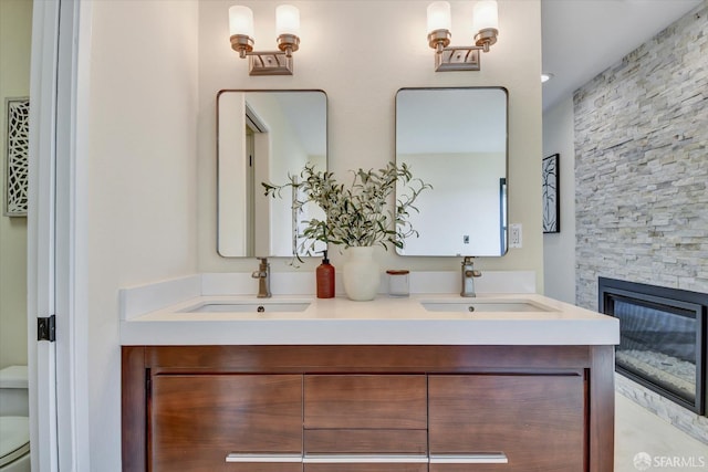 bathroom featuring toilet, vanity, and a stone fireplace