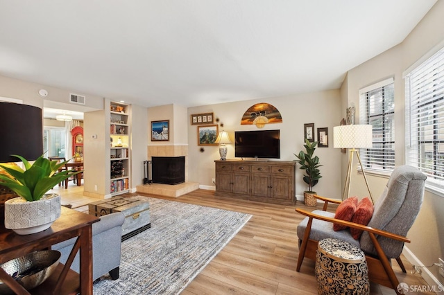 1421 El Camino Real Unit 3, Burlingame, CA 94010 - living area featuring light wood-type flooring, a tiled fireplace, baseboards, and built in shelves