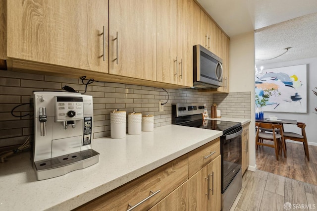 kitchen featuring appliances with stainless steel finishes, light brown cabinets, light hardwood / wood-style floors, backsplash, and light stone counters