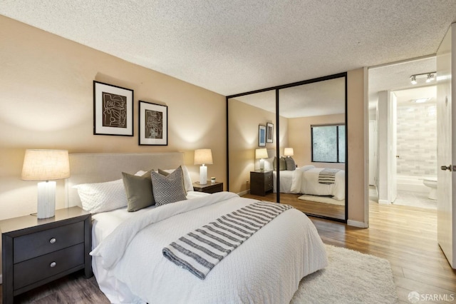 bedroom featuring ensuite bath, wood-type flooring, a closet, and a textured ceiling