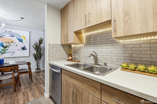 kitchen with decorative backsplash, wood-type flooring, a textured ceiling, stainless steel dishwasher, and sink