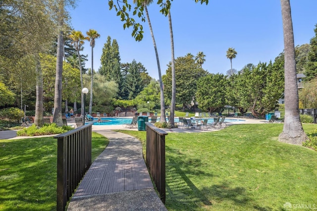 view of property's community with a swimming pool and a lawn