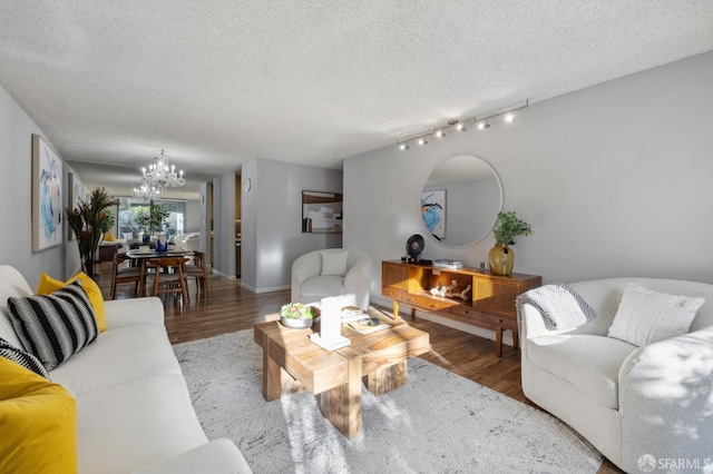 living room with hardwood / wood-style flooring, a textured ceiling, track lighting, and an inviting chandelier