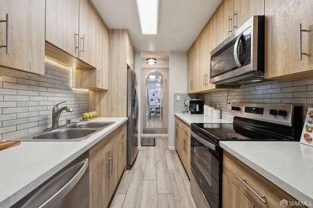 kitchen featuring decorative backsplash, sink, light hardwood / wood-style flooring, and stainless steel appliances