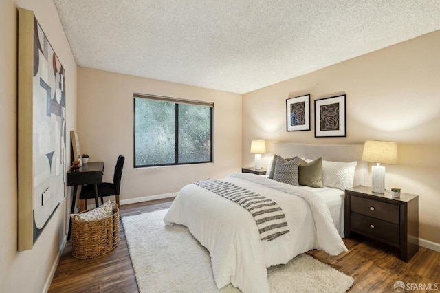 bedroom with a textured ceiling and dark hardwood / wood-style flooring