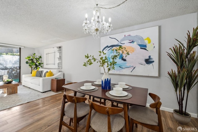 dining area with an inviting chandelier, a textured ceiling, and hardwood / wood-style floors