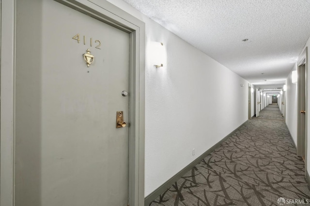 hall with a textured ceiling and carpet