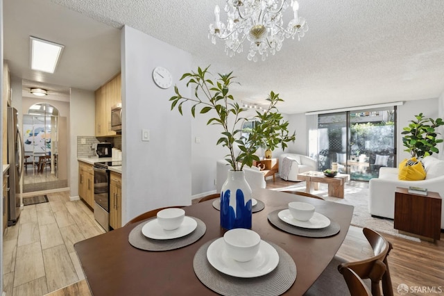 dining space featuring a textured ceiling, an inviting chandelier, floor to ceiling windows, and light wood-type flooring