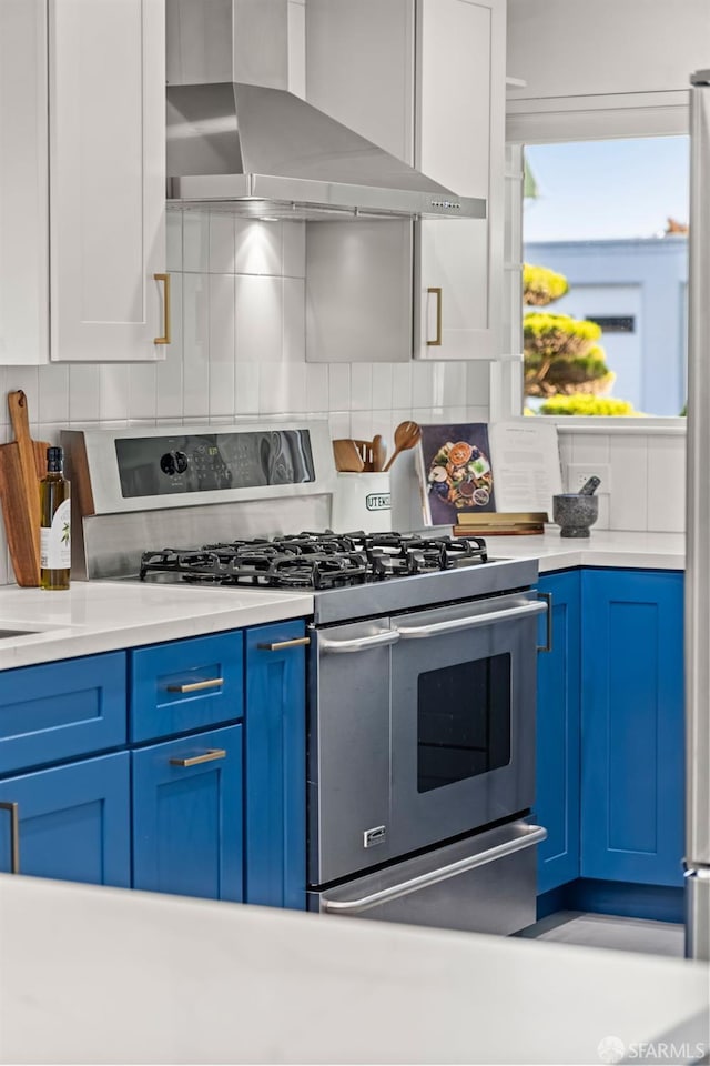 2811 Bayview Dr, Alameda, CA 94501 - kitchen with double oven range, wall chimney exhaust hood, blue cabinetry, tasteful backsplash, and light countertops