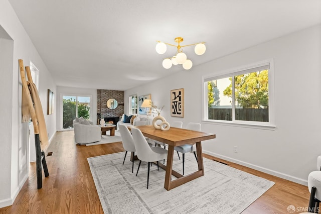 2811 Bayview Dr, Alameda, CA 94501 - dining room featuring a fireplace, a chandelier, wood finished floors, and baseboards