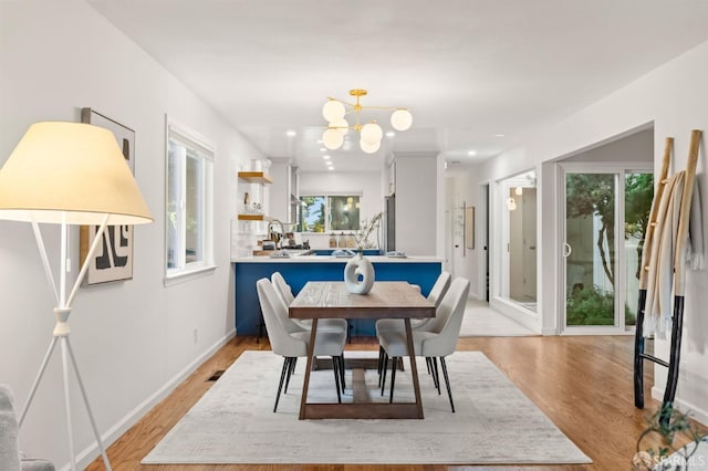 2811 Bayview Dr, Alameda, CA 94501 - dining room featuring a chandelier, light wood-style floors, and baseboards