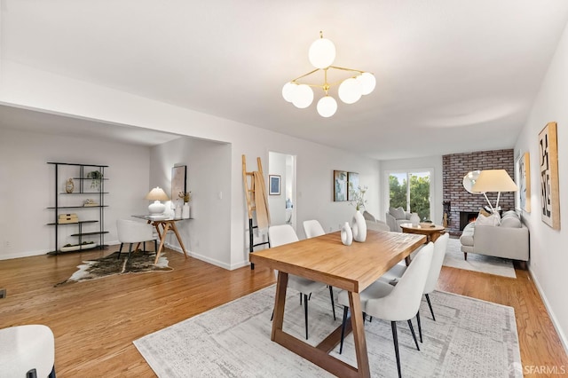 2811 Bayview Dr, Alameda, CA 94501 - dining room featuring light wood-style floors, a chandelier, a fireplace, and baseboards
