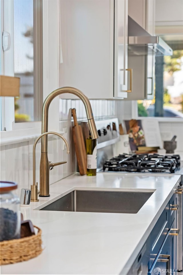2811 Bayview Dr, Alameda, CA 94501 - kitchen with blue cabinetry, a sink, light countertops, decorative backsplash, and under cabinet range hood