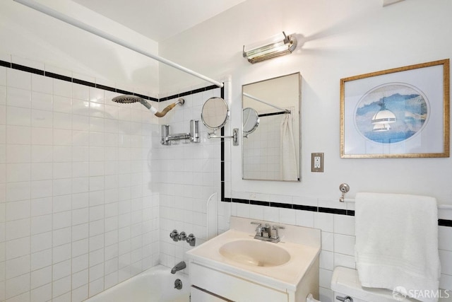 full bathroom featuring tiled shower / bath, vanity, toilet, and tile walls