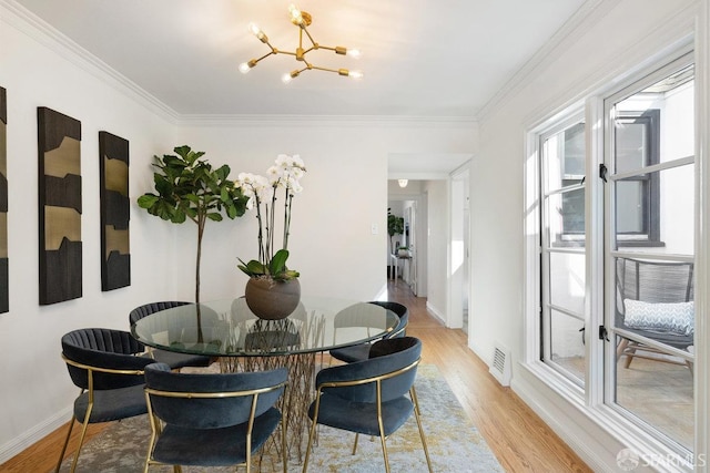 dining space with ornamental molding, a notable chandelier, and light wood-type flooring