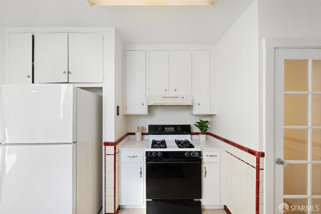 kitchen with gas stove, white fridge, tile walls, and white cabinets