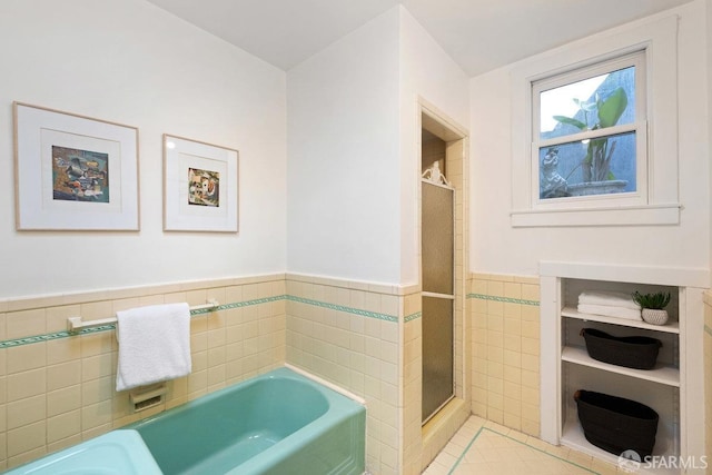 bathroom with a bath, tile patterned flooring, and tile walls