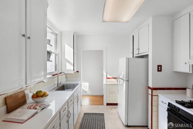 kitchen with sink, gas range oven, white cabinets, and white refrigerator