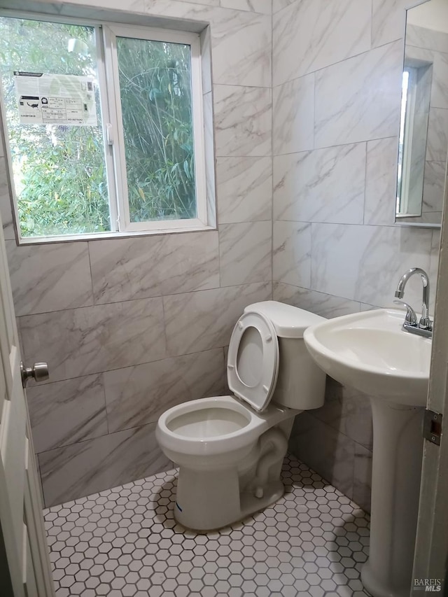 bathroom with toilet and tile walls