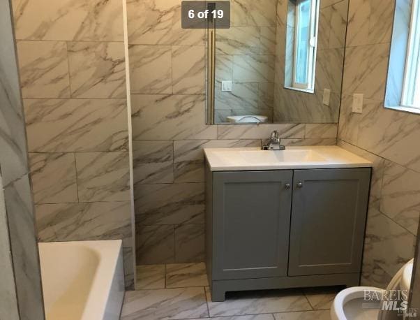 full bathroom with vanity, independent shower and bath, toilet, and tile walls