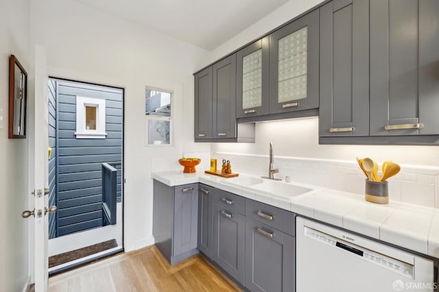 kitchen with dishwasher, sink, gray cabinetry, and tile counters