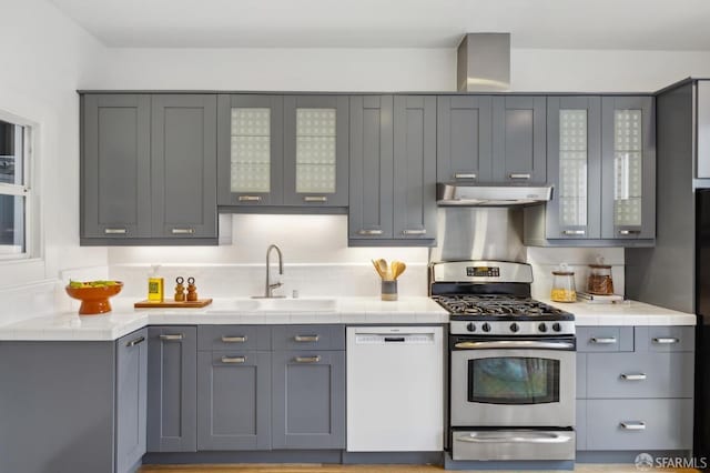 kitchen with sink, gray cabinets, backsplash, white dishwasher, and stainless steel range with gas cooktop