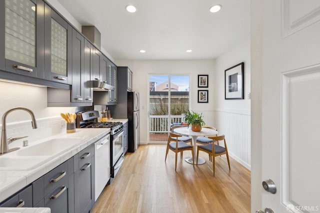 kitchen featuring gray cabinets, tasteful backsplash, sink, light hardwood / wood-style floors, and stainless steel appliances