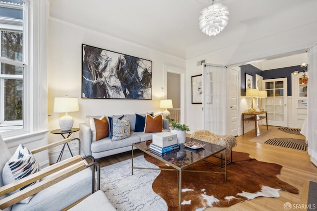 living room featuring hardwood / wood-style flooring, crown molding, and a chandelier