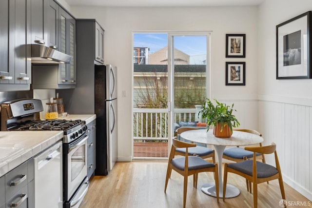 kitchen featuring tile countertops, stainless steel appliances, light hardwood / wood-style floors, and gray cabinets