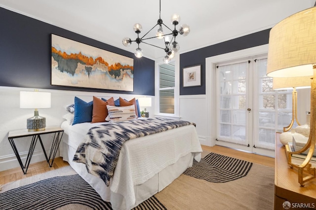 bedroom with crown molding, an inviting chandelier, and light wood-type flooring