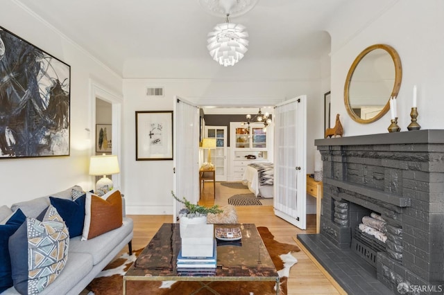 living room with hardwood / wood-style flooring, crown molding, and a chandelier