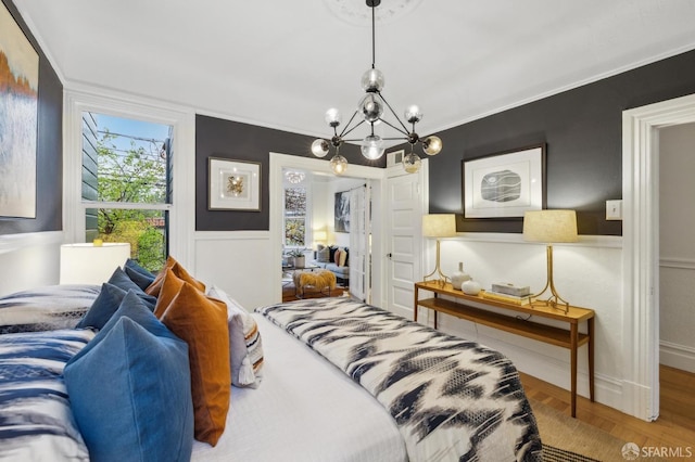 bedroom featuring an inviting chandelier, wood-type flooring, and ornamental molding