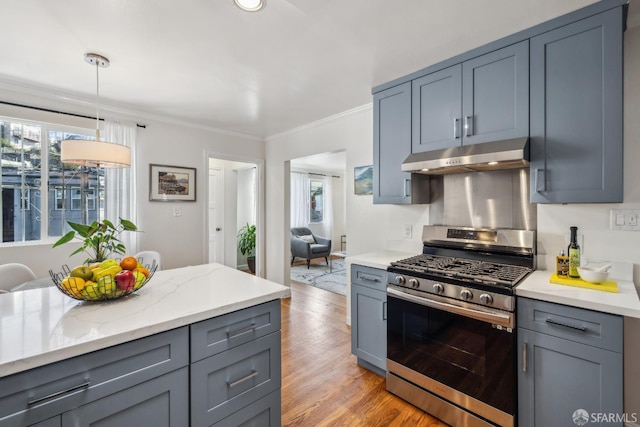 kitchen with under cabinet range hood, light wood-style floors, ornamental molding, stainless steel gas range, and gray cabinets