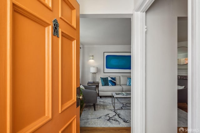 hall with ornamental molding and wood finished floors