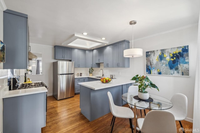 kitchen with a peninsula, light wood finished floors, light countertops, and freestanding refrigerator