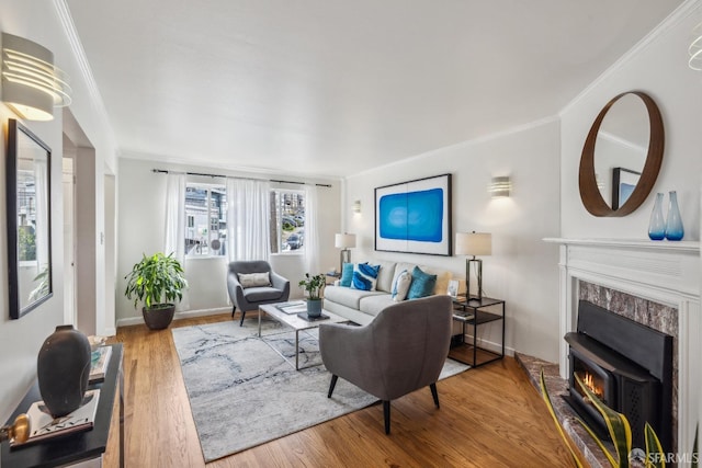 living room with ornamental molding, a fireplace, wood finished floors, and baseboards