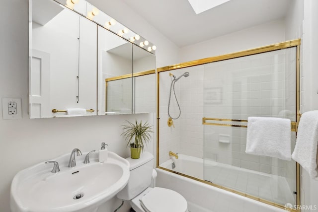 full bathroom with a skylight, shower / bath combination with glass door, a sink, and toilet